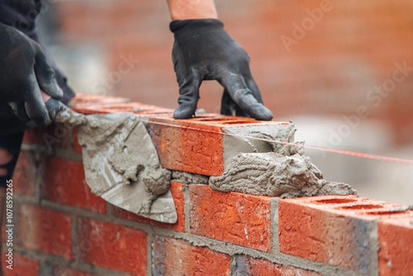 Obraz Skilled mason laying bricks with precision and attention to detail during construction in bright daylight