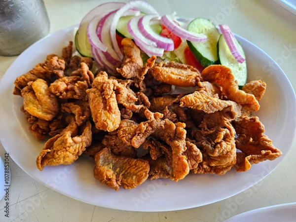 Fototapeta A plate of Fish crackling with a side of vegetables. The vegetables include onions, cucumbers, and tomatoes