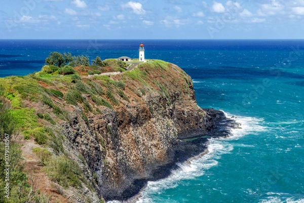 Fototapeta Built in 1913 atop a lava rock peninsula on the north shore of the Hawaiian Island of Kauai, Daniel K. Inouye Kilauea Point Lighthouse stands over the blue Pacific Ocean as waves break below.