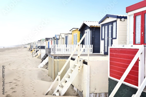 Fototapeta Beach huts or houses and blue sky. Multicolored beach bathing huts with white sand and clear blue sky. Beach scene with copy space.