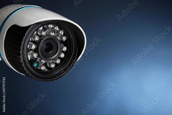 Fototapeta Security CCTV camera on blue background, closeup