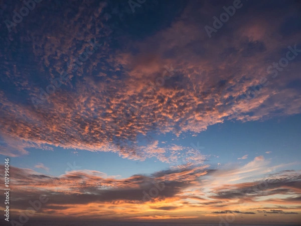 Fototapeta Sunset over the Atlantic Ocean composing a dramatic orange cloud
