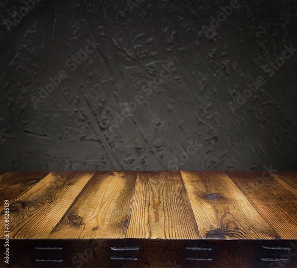 Fototapeta  An empty wooden countertop against a black, dark concrete wall. Home interior. Evening, dim light. Space for text. Copy space
