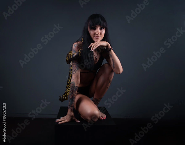 Obraz Photo of the brunette woman squatting with python