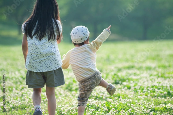 Obraz シロツメクサの花畑でたたずむ姉弟の後姿