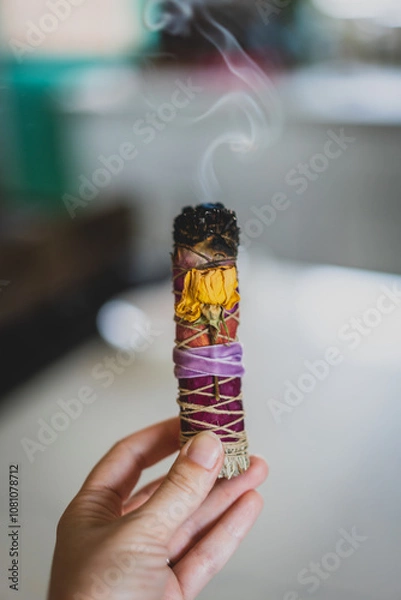 Obraz closeup of hand holding burning sage stick with smoke wrapped with flowers