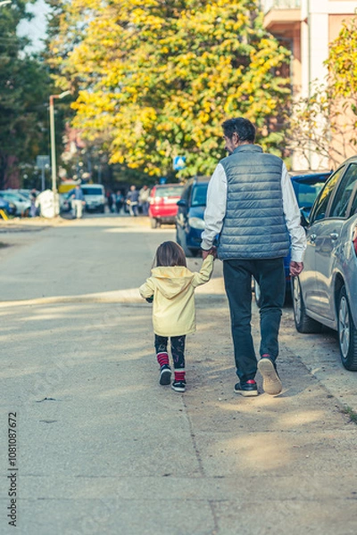 Obraz A grandpa is taking his granddaughter for a walk on a sunny autumn day