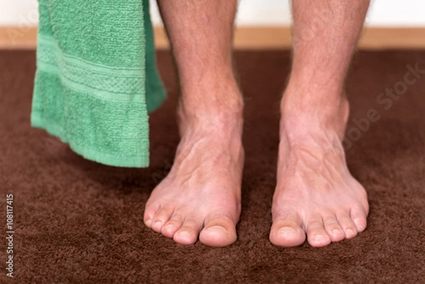 Obraz Healthy male feet with towel stepping towards the bathroom.