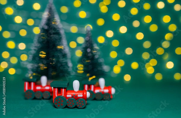 Fototapeta A photo of a Christmas trains with a selective focus. Christmas decorations. Christmas background. Bright bokeh. Green background. Children's toy and a Christmas decoration
