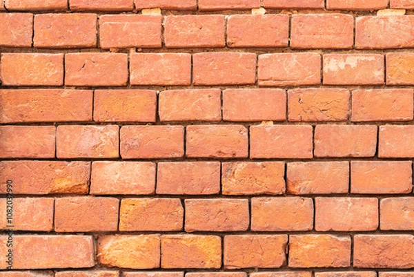 Fototapeta Aged red brick wall with signs of wear and tear. texture background