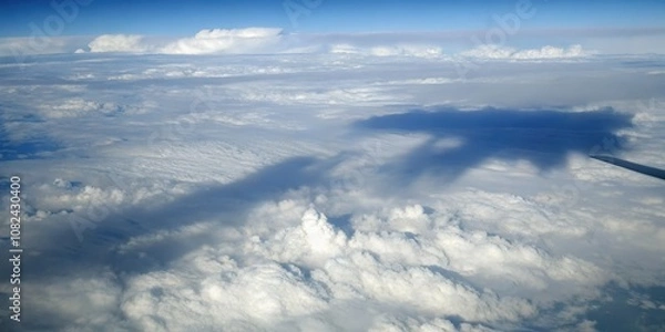 Fototapeta Aerial view of fluffy white clouds from an airplane window with a blue sky
