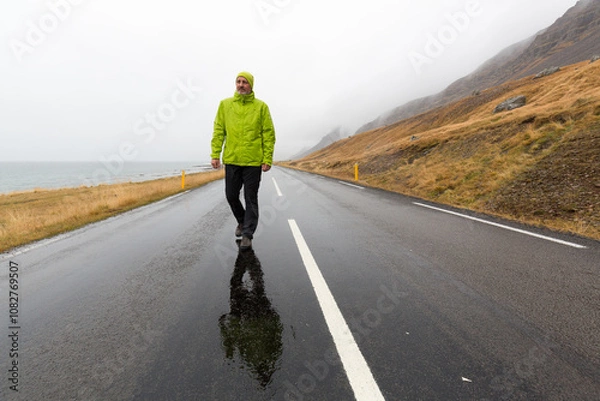 Obraz Ein Mann mit Regenjacke auf einer einsamen Straße in einer einsamen Gegend