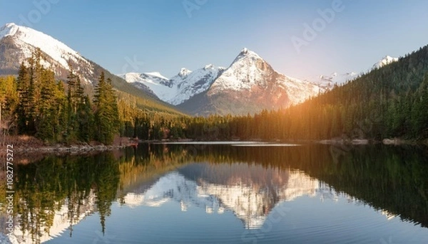 Fototapeta Serene Lake Nestled Between Snow-Capped Peaks and Lush Forests, Reflecting the Sunshine and Surrounding Scenery on Its Glassy Surface During Early Morning