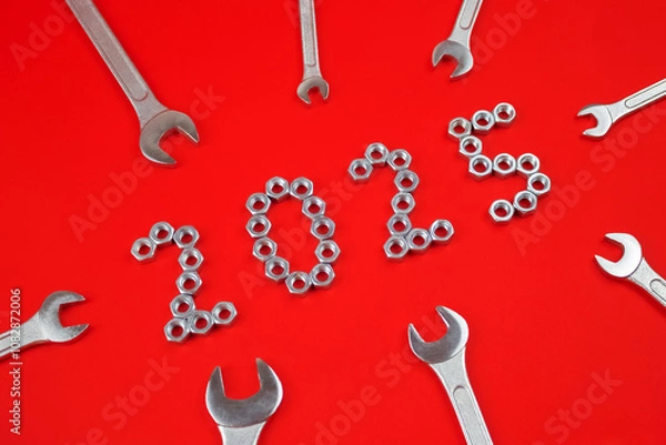 Fototapeta Number 2025 by metal nuts and wrenches on a red background. 2025 year