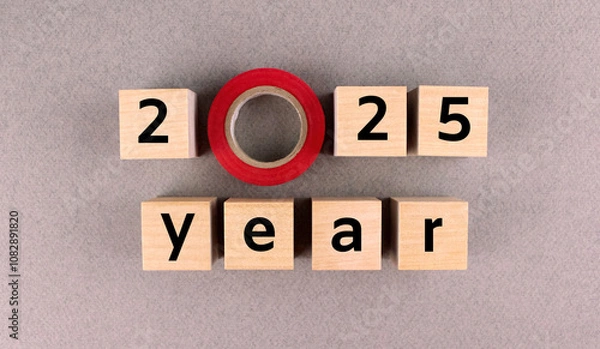 Fototapeta Wooden cubes with numbers and letters with electrical tape lined with inscription 2025 on a gray background