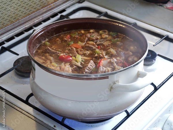 Fototapeta oriental soup kharcho of beef, rice, tomatoes, tkemali plum puree, fried onion and cilantro. steam over boiling soup in big open pot on gas stove