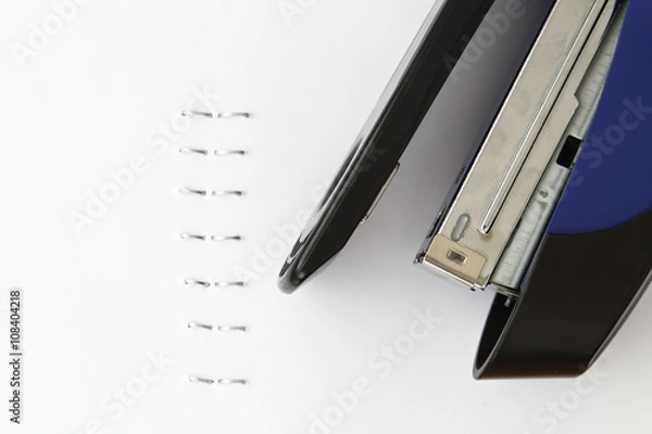 Fototapeta Blue stapler and staples with paper on the table