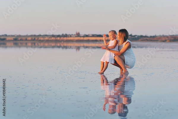 Fototapeta Мама играет с маленькой дочерью в море на закате