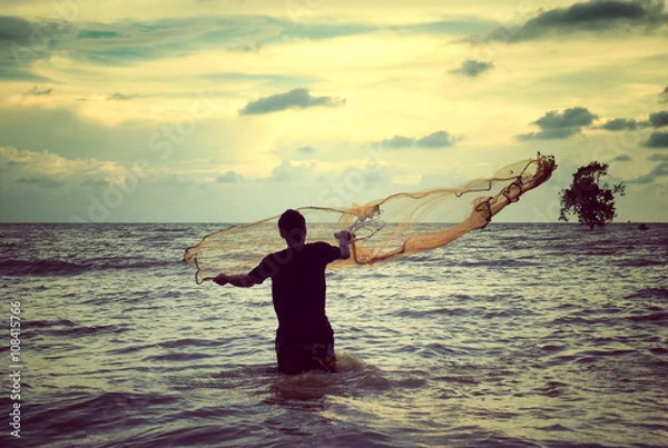 Obraz retro look image of a man throwing fishing net with sunset background