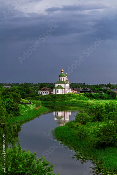 Fototapeta SUZDAL, RUSSIA - Beautiful landscape of Suzdal overlooking the Kamenka River and the ancient Russian Church of Elijah the Prophet (Ilyinsky Church)At sunset