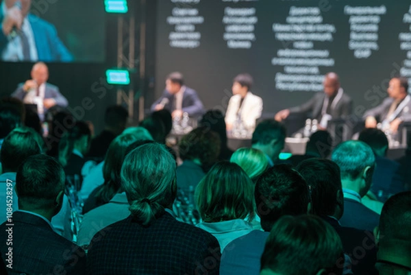 Obraz Audience attending business conference panel discussion with professionals on stage. Engaging atmosphere promoting knowledge exchange.