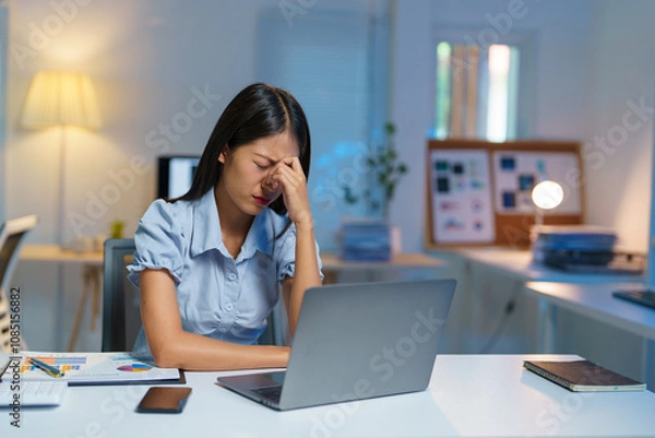 Fototapeta Stressed, tired, sleepy businesswoman bored from sitting at a desk for long hours and having office syndrome while working with laptop and financial paperwork. Office marketing.