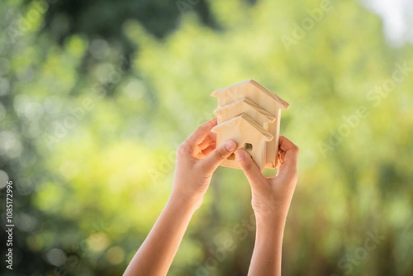 Obraz Man hand hold for select the three home model on sunlight in the public park, Loan for real estate or saving money for buy a new house to family in the future concept.