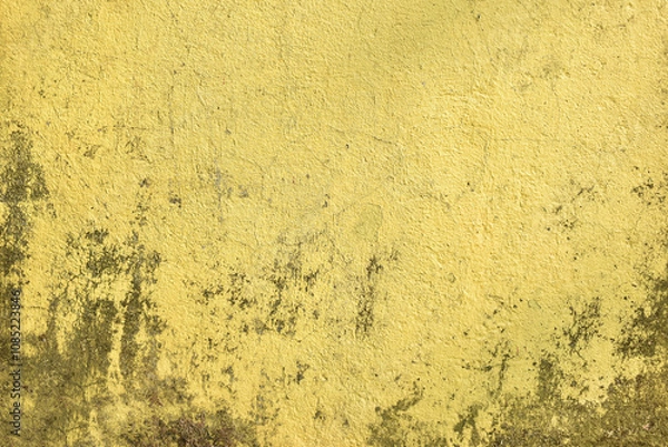 Fototapeta Grungy yellow wall texture with aged and weathered details. Old rustic surface with cracked and stained yellow paint. Vintage textured background in yellow with dark patches.