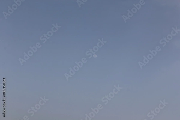 Fototapeta A crescent moon above the desert horizon in twilight, creating a peaceful, dreamlike scene.