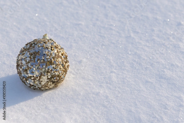 Obraz A golden bauble with gold decorations lying on white natural snow  on a sunny frosty day.