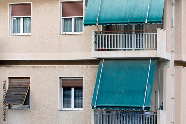 Fototapeta close up on the facade of an apartment building in Athens, Greece with green awnings. 