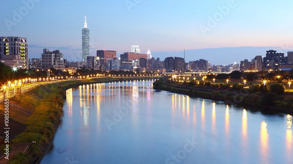 Fototapeta Beautiful riverside scenery of busy Taipei City with view Taipei 101 Tower, Keelung River and downtown area at dusk ~ A Blue and Gloomy evening in Taipei