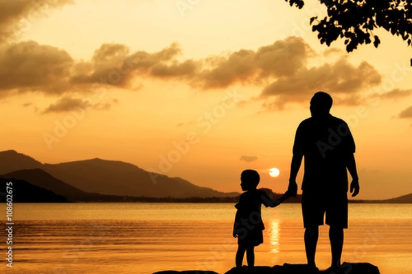Fototapeta Silhouette of standing on the beach sunset background