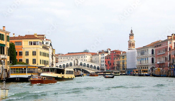 Fototapeta A view of historic Venetian buildings along the Grand Canal, showcasing classic Italian architecture. The iconic canal waters reflect the facades, with boats and gondolas adding to the charm of Venice