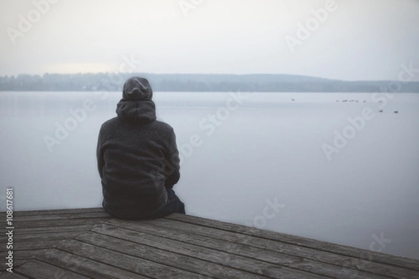 Fototapeta Samotny mężczyzna siedzący na pomoście nad jeziorem lub rzeką / Lonesome Huy At The Lake