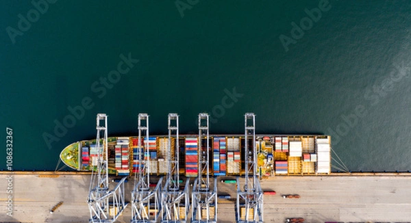 Obraz Top view of a large cargo ship loading and unloading containers at a deep sea port. Aerial view of international shipping and logistics hu