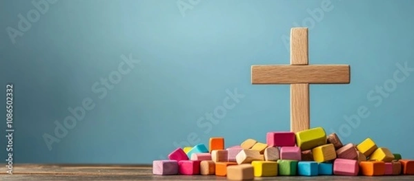 Fototapeta Wooden cross surface pile colorful blocks scattered around Christian themed craft supplies