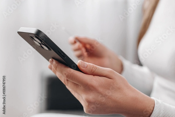 Obraz Close up of woman hands holding credit card and smartphone, young female paying online, using banking service, entering information, shopping, ordering in internet store, girl doing secure payment
