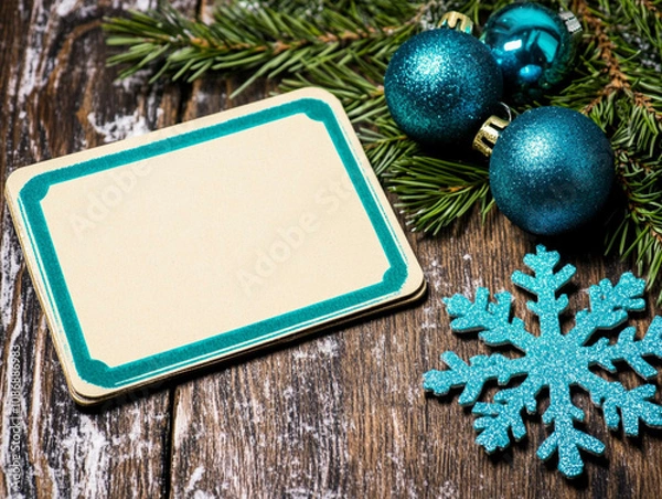 Fototapeta Holiday table decorations, top view: a blank centerpiece framed with natural pine branches, shimmering blue ornaments, intricate snowflakes and a small wrapped gift. Balanced composition for creating 