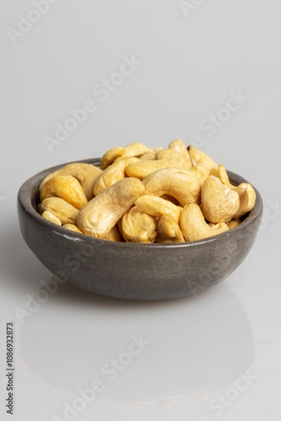 Obraz Cashew nuts in grey bowl on white background. 
