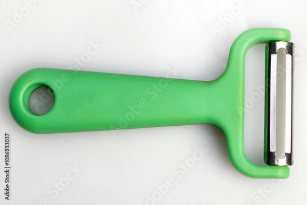 Fototapeta Green vegetable peeler with stainless steel blade isolated on white background. Kitchen utensils and equipment