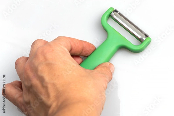 Obraz Green vegetable peeler with stainless steel blade isolated on white background. Kitchen utensils and equipment