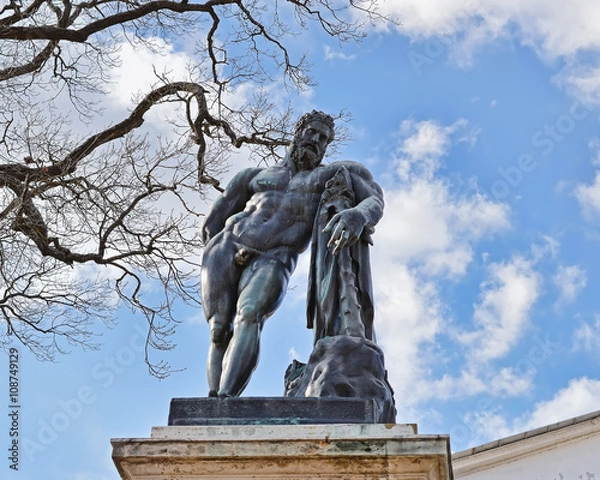 Obraz Бронзовая скульптура Геракла на пьедестале на фоне неба.
