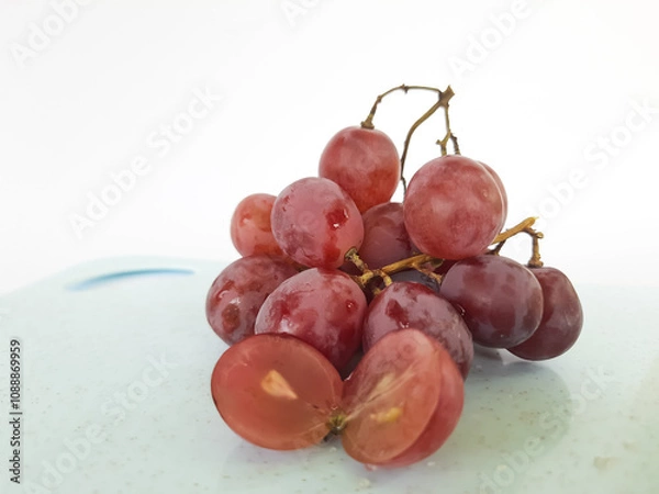 Fototapeta red grapes on a wooden plate and on a cutting board on a white background
