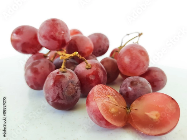 Fototapeta red grapes on a wooden plate and on a cutting board on a white background