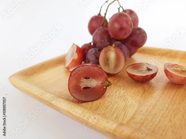 Fototapeta red grapes on a wooden plate and on a cutting board on a white background