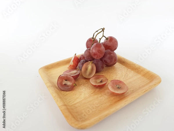 Fototapeta red grapes on a wooden plate and on a cutting board on a white background