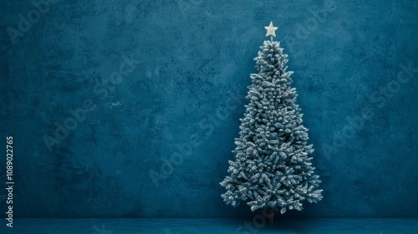 Obraz Snowy Christmas tree against a blue wall backdrop.