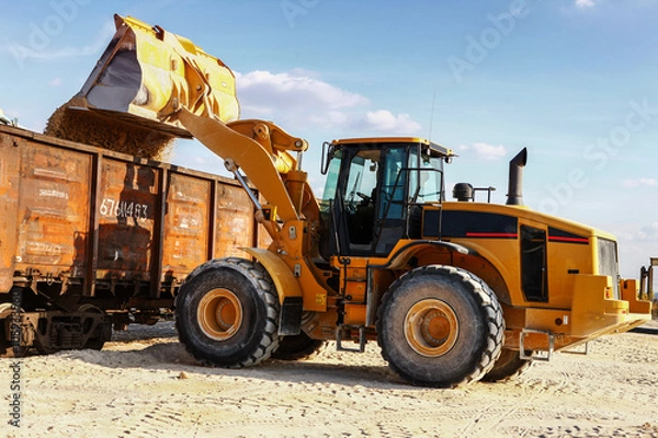 Obraz Loader loads the wagon train transport against cloud sky