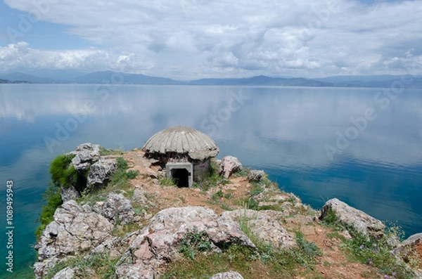Fototapeta An abandoned concrete bunker sits perched on a rocky outcrop in the Lin village in Albania, overlooking the Ohrid Lake, a natural border between Albania and North Macedonia